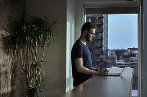 man standing beside table using laptop
